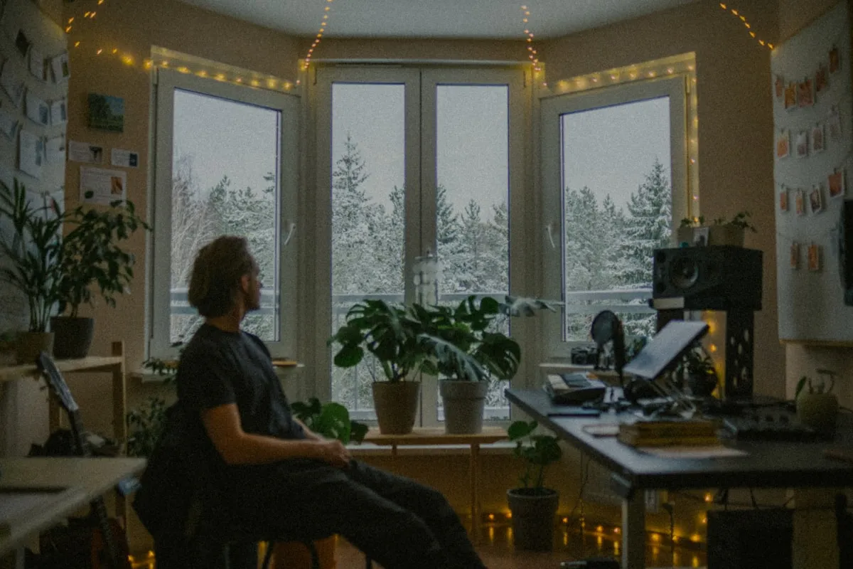 A person looking out a window at snow-covered trees