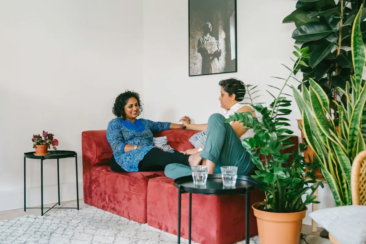 Two people in conversation on a couch in a bright room