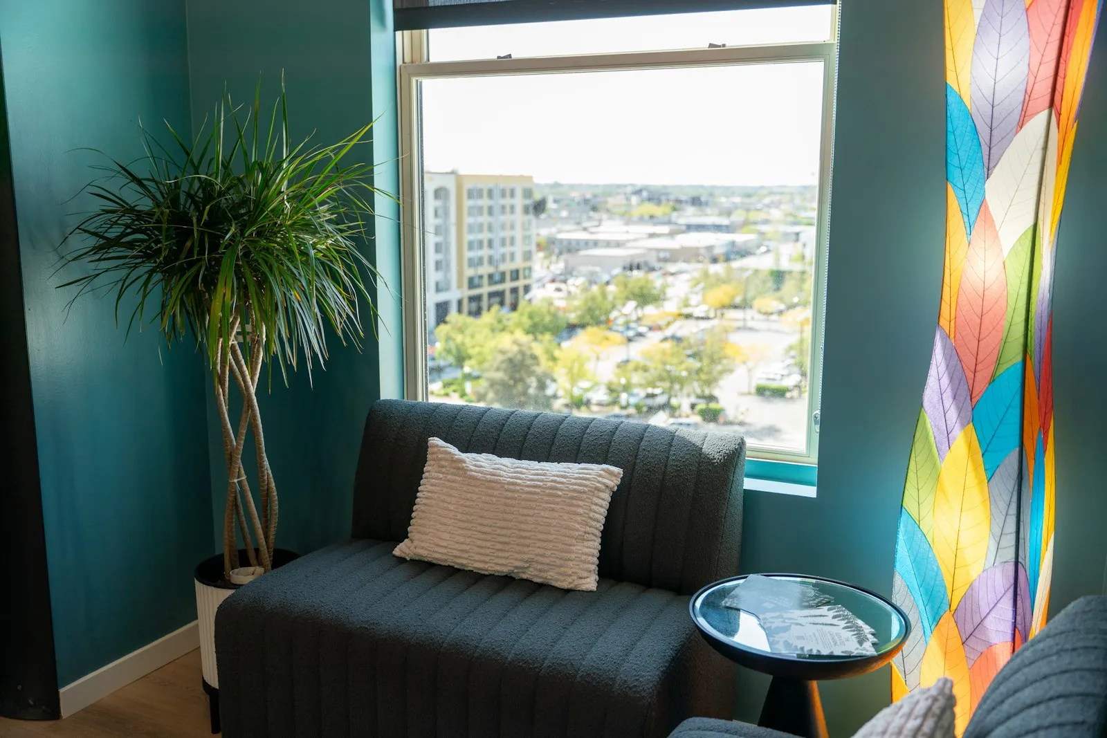 A calm therapy room with a couch, plant, and a view outside